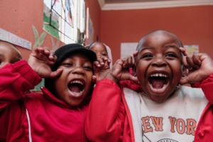 two elementary-age black children smile wide and make silly faces at the camera. 